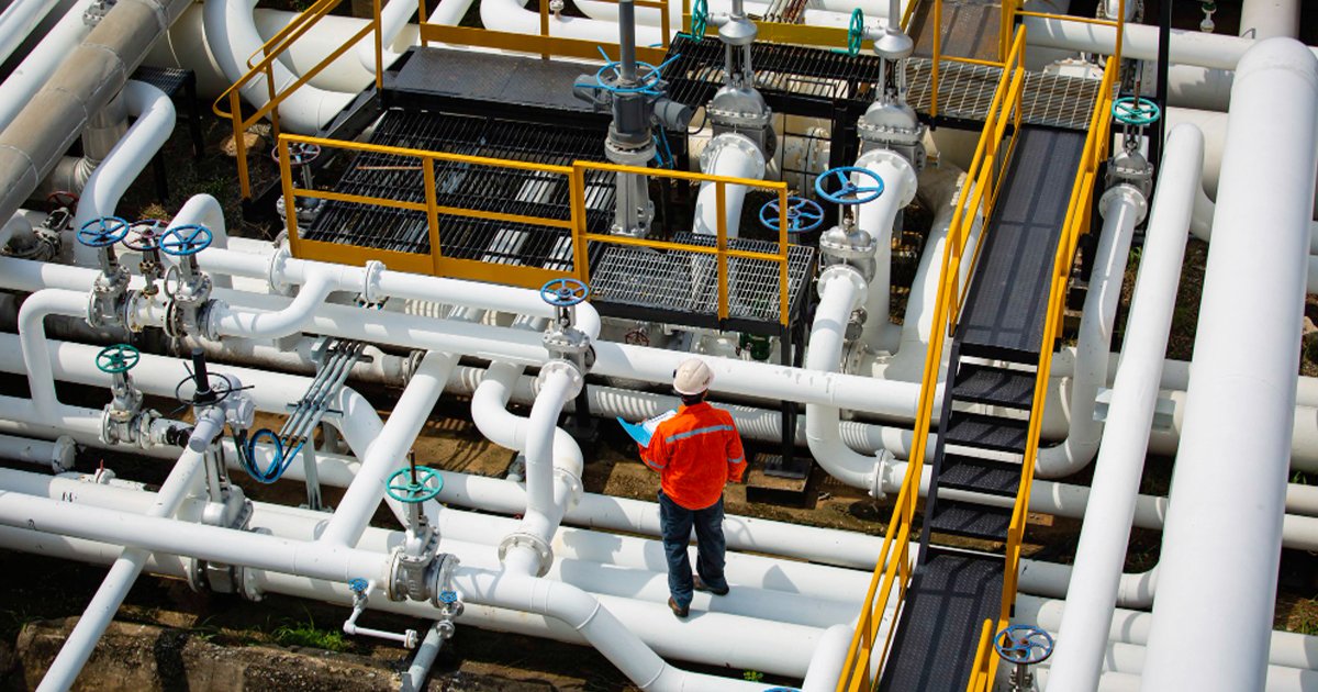 A MEP worker wearing an orange shirt stands confidently on a pipe, showcasing his expertise and dedication to his job.