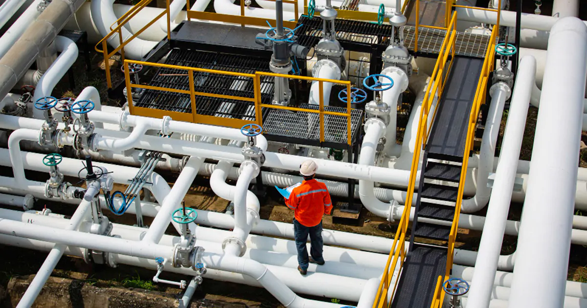 A MEP worker wearing an orange shirt stands confidently on a pipe, showcasing his expertise and dedication to his job.